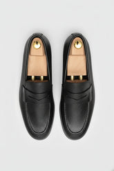 Black textured leather slip-on loafer with elegant design and comfortable fit.
